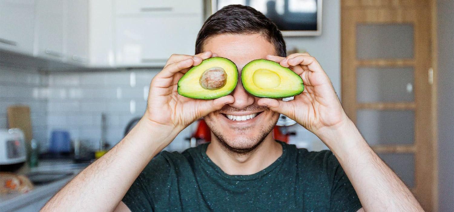 man with avocado in hands near the face